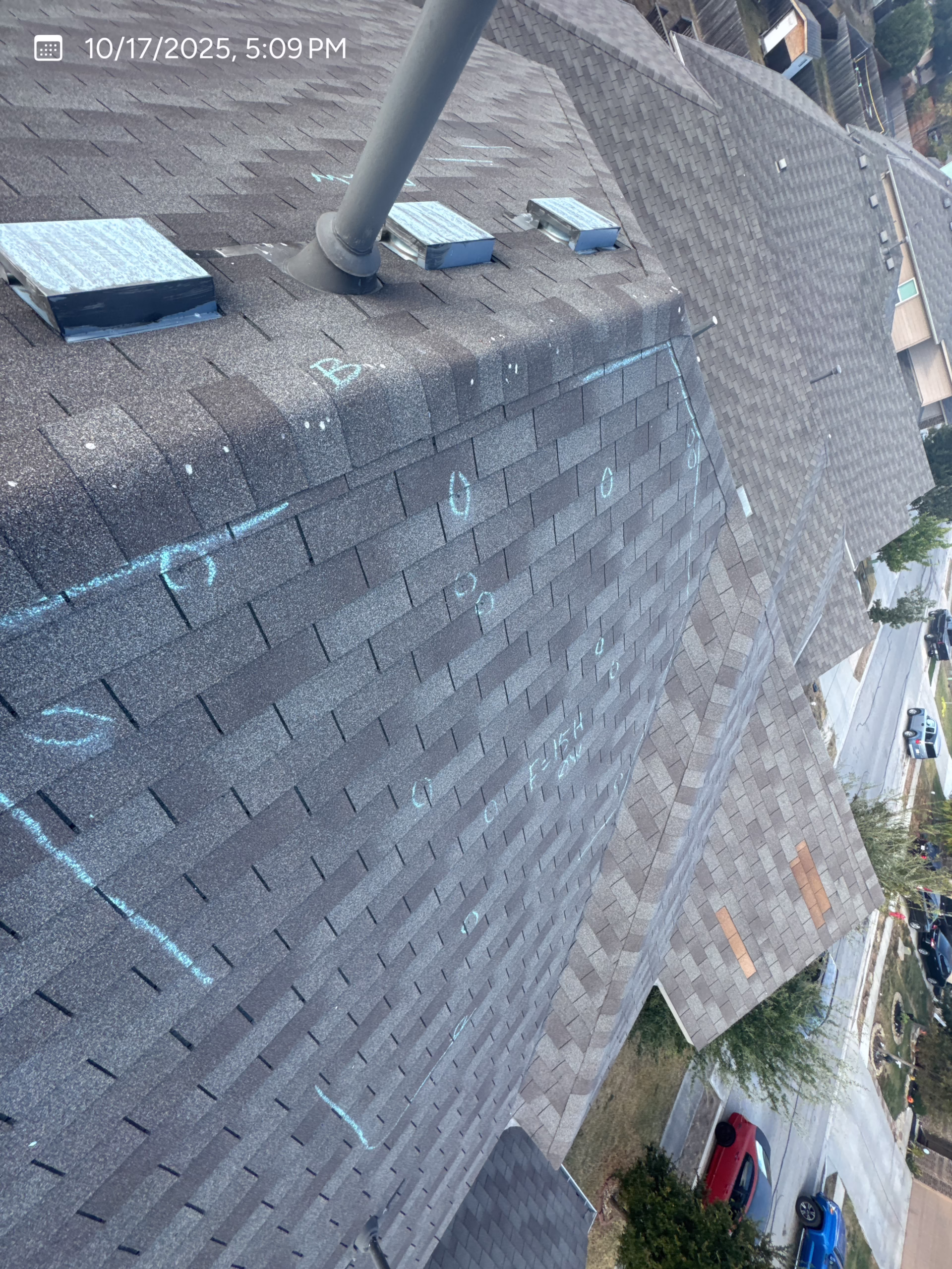 roof inspector marking hail damage test squares on shingles